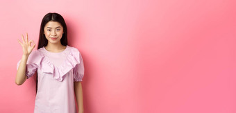 微笑亚洲女人衣服显示标志<strong>赞美赞美</strong>好事情批准优秀的选择站粉红色的背景