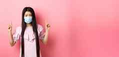 健康的人科维德流感大流行概念伤心亚洲女孩感觉生病的穿医疗面具self-quarantine站粉红色的背景