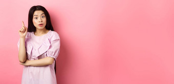 兴奋亚洲女人投手的想法提高手指尤里卡标志计划解决方案站粉红色的背景