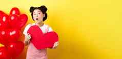 快乐情人节一天愚蠢的亚洲女孩显示大红色的心明信片惊讶站红色的浪漫的气球黄色的背景
