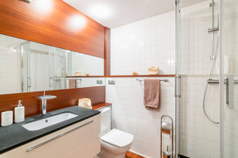 浴室墙深焦糖木镶板大镜子对比白色水槽建黑色的大理石工作台面镜子反映了淋浴小屋玻璃门
