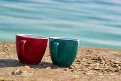 红色的绿色陶瓷杯咖啡茶饮料海岸岩石海湾