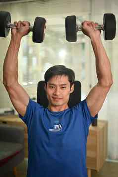 强大的年轻的亚洲男人。提升哑铃早....锻炼首页健康的生活方式健身概念