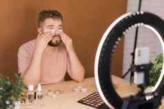 男人。会说话的化妆品持有化妆工具记录视频的家伙使视频博客化妆品产品