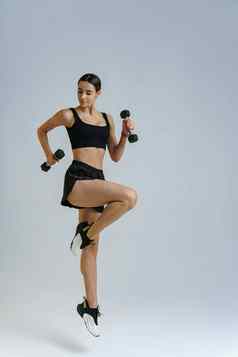 健身女人穿运动服装有氧运动练习哑铃工作室背景