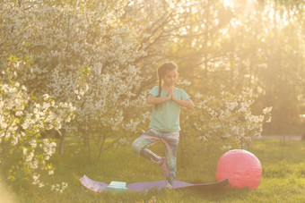 女孩t恤瑜伽席花园孩子健康的生活方式