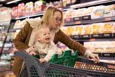 高加索人妈妈。购物婴儿婴儿男孩孩子选择产品部门超市杂货店商店
