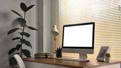 现代工作场所室内白色空白屏幕电脑监控图片框架灯书木桌子上