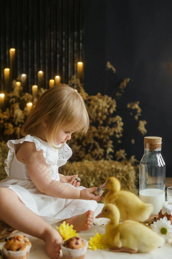 女孩坐着复活节表格玩可爱的毛茸茸的小鸭概念庆祝快乐复活节