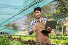 年轻的亚洲农民农民记录数据农场收集检查蔬菜移动PC