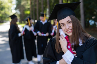 集团快乐学生毕业礼服在户外年轻的女孩拥有文凭