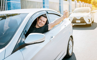 微笑司机给拇指路满意司机男人。显示拇指安全开车概念年轻的司机男人。车显示拇指