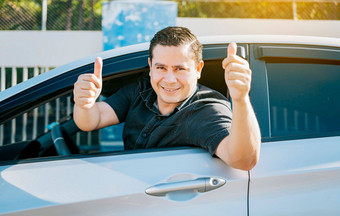 快乐司机给拇指路安全开车概念满意司机男人。显示拇指年轻的司机男人。车显示拇指