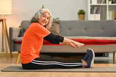运动高级夫人伸展运动腿席首页锻炼退休健康的生活方式概念