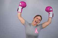 女人粉红色的丝带胸部提出了手粉红色的拳击手套灰色的背景胜利乳房癌症