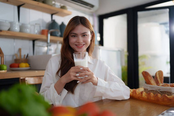 肖像年<strong>轻</strong>的快乐的亚洲女人喝牛奶厨房房间健康的生<strong>食</strong>物素<strong>食主义</strong>幸福健康的生活方式概念