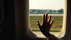 孩子手触碰飞机窗口关闭轮廓孩子的棕榈背景窗口飞机概念安全航班