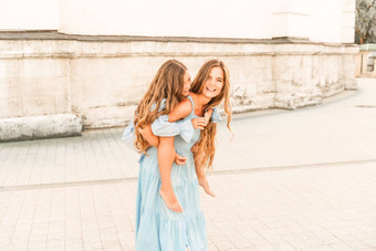 妈妈。女儿走玩妈妈。持有女孩回来持有腿女儿拥抱肩膀穿着蓝色的礼服