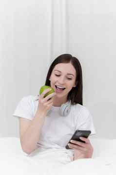 肖像好健康的女人吃绿色苹果休息床上卧室生活方式首页概念