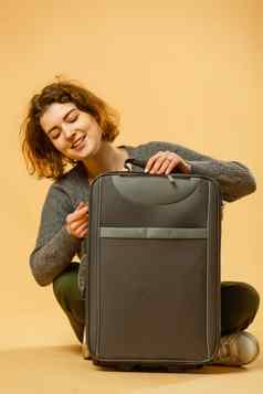 准备好了假期旅行概念年轻的兴奋女人坐着行李手提箱孤立的