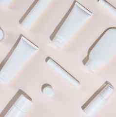 白色塑料管罐子形式包装化妆品米色背景前视图