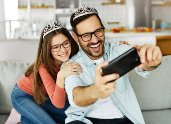 孩子女儿女孩家庭快乐父亲玩有趣的女孩快乐的微笑首页公主玩具皇冠成键爱自拍相机移动电话智能手机照片图片肖像