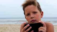 可爱的男孩海滩电子平板电脑特写镜头