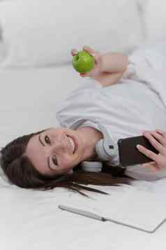 肖像好健康的女人吃绿色苹果休息床上卧室生活方式首页概念