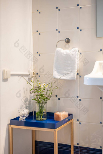 角落里浴室装饰低装饰表格蓝色的基地表格花瓶野生花平铺的墙持有人白色特里毛巾