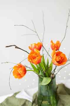 美丽的春天花束绿色花瓶站表格亚麻桌布橙色牡丹郁金香