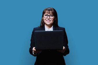 成熟的业务女人摆姿势移动PC蓝色的工作室背景
