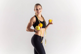运动金发女郎女人完美的身体持有苹果橙色新鲜的水果汁手