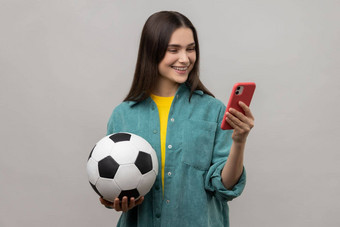 很高兴女人站持有足球球聪明的电话表达积极的情绪