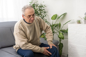 男人。膝盖联合疼痛沙发疼痛上了年纪的<strong>健康</strong>护理上了年纪的护理上了年纪的男人。膝盖疼痛坐着祖父膝盖疼痛