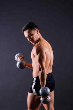 肖像年轻的健身运动强大的男人。bare-chested肌肉发达的运动员孤立的灰色黑暗