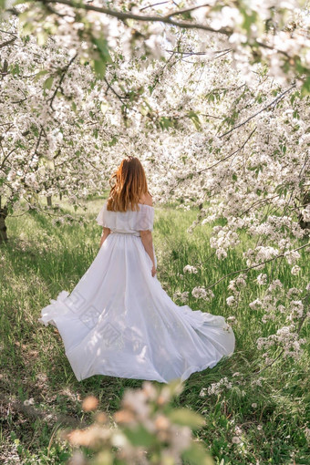 幻想女人长白色优雅的时尚长衣服走绿色春天开花樱桃花园快乐快乐的女孩公主新娘裙子织物苍蝇流动挥舞着风运动