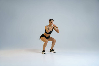<strong>健身</strong>女人深蹲锻炼工作室背景锻炼概念