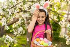 可爱的孩子女孩穿兔子耳朵复活节一天女孩狩猎复活节鸡蛋草坪上房子女孩持有篮子画鸡蛋