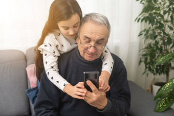 高级祖父学习移动电话<strong>指导</strong>漂亮的年轻的（外）孙女坐着沙发首页