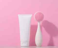 白色塑料管按摩刷面部清洗粉红色的背景项目化妆品程序