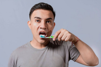 英俊的的家伙刷牙牙齿孤立的关闭英俊的男人。刷牙牙齿刷牙牙科卫生概念关闭人刷牙牙齿孤立的背景