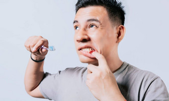 男人。持有牙刷口香糖疼痛孤立的人持有牙刷口香糖问题孤立的年轻的男人。牙龈炎持有牙刷人持有牙刷口香糖疼痛