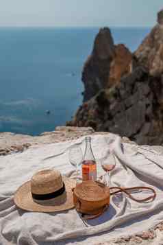 野餐毯子香槟眼镜他稻草钱包前山背景海岩石海