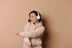 快乐中年女人无线耳机听声音跟踪播放列表移动音乐孤立的米色背景