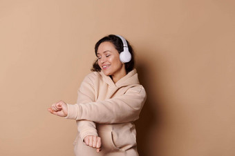 快乐中年女人无线耳机听<strong>声音</strong>跟踪<strong>播放</strong>列表移动音乐孤立的米色背景