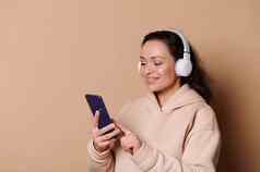 美丽的快乐女人无线耳机测试移动应用程序滚动播放列表听音乐