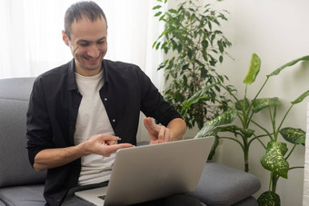 年轻的男人。显示手势标志语言移动PC使视频调用