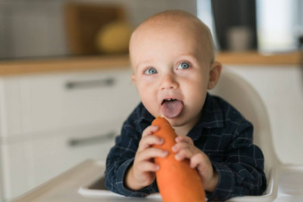 男孩蓝色的t恤坐着孩子的椅子吃胡萝卜复制空间空空间文本<strong>婴儿护理婴儿</strong>孩子喂养概念