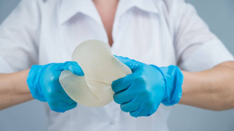 塑料外科医生演示了强度硅胶乳房植入物挤压