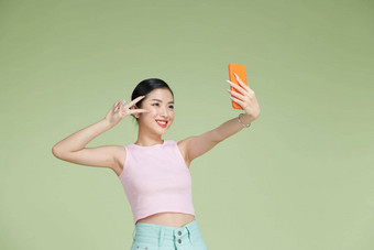 微笑可爱的亚洲女使自拍照片智能手机积极的表达式绿色背景